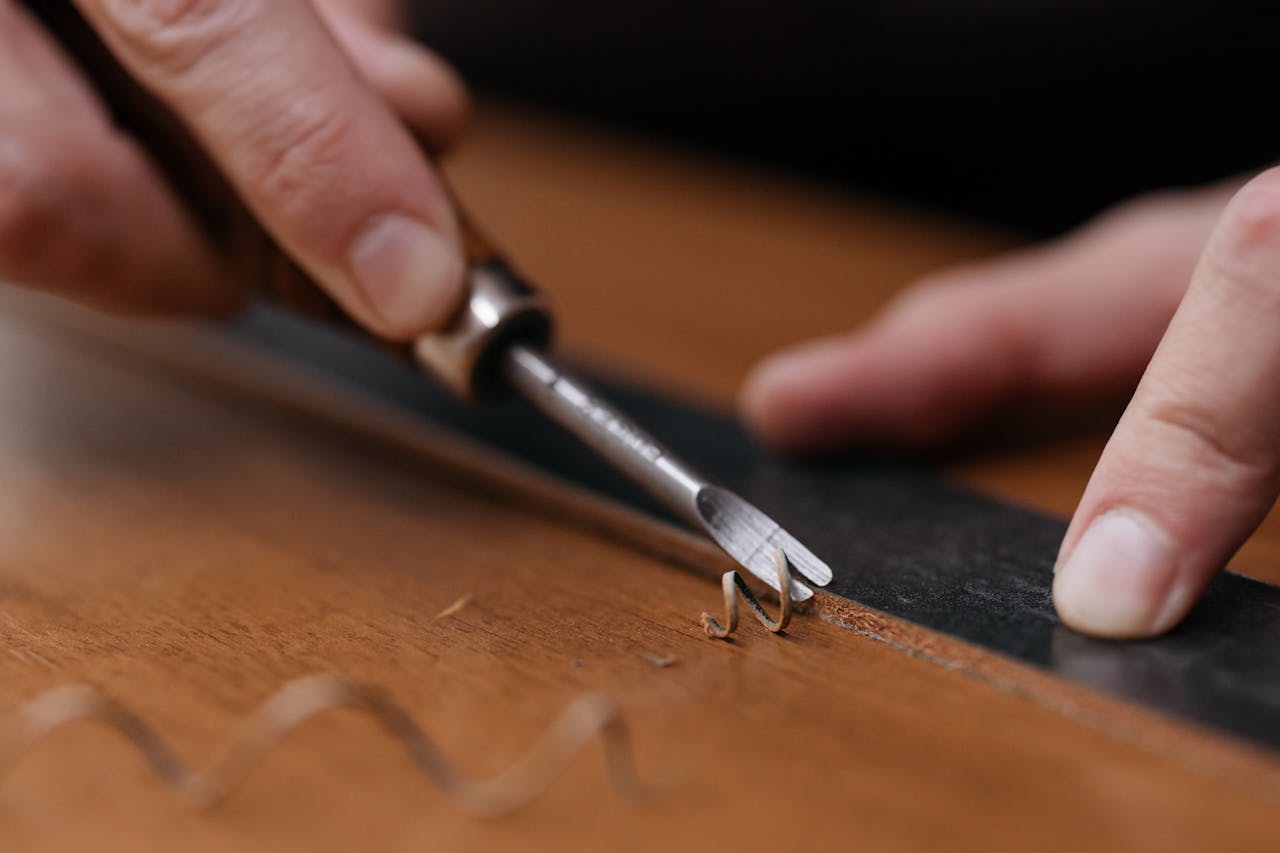 Close-up of hands carving wood with a chisel and ruler, showcasing fine craftsmanship.